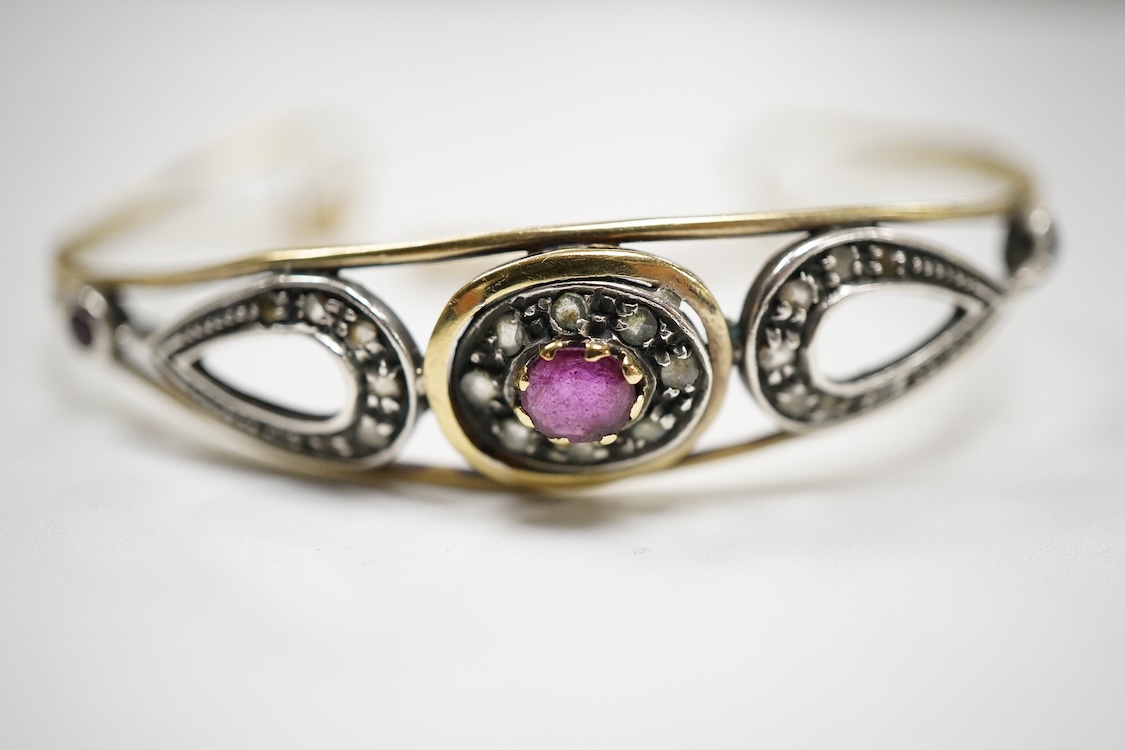 An Italian 18k and white metal, ruby and diamond cluster set bangle, with safety chain, gross weight 10.1 grams.